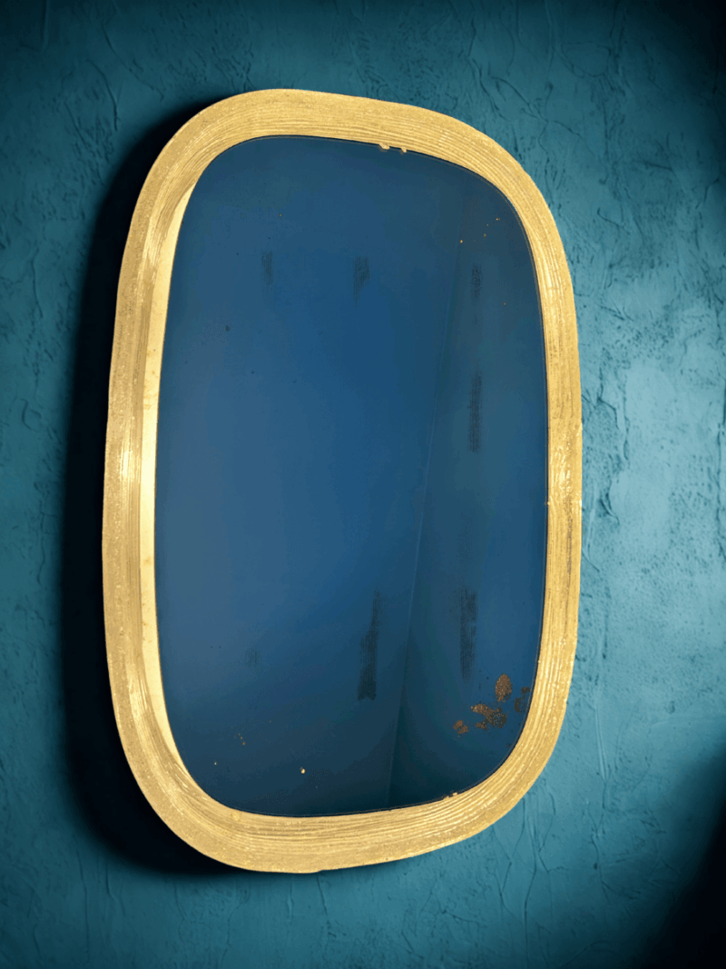 Miroir lumineux vintage accroché à un mur bleu texturé – ambiance chaleureuse et rétro.